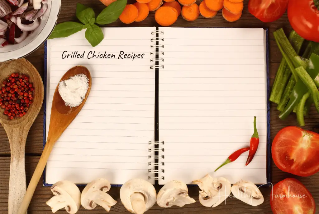 Open notebook with words 'Grilled Chicken Recipes', spoons, and veggies.