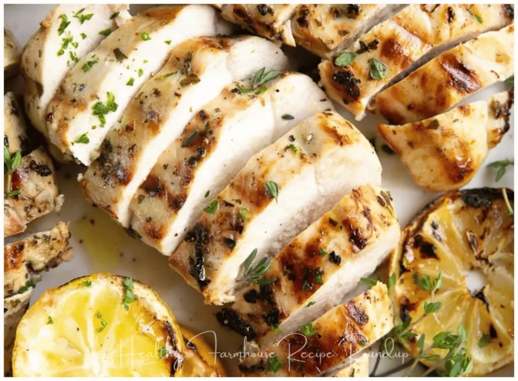 Grilled Greek chicken breast recipe sliced with lemon slices and herbs