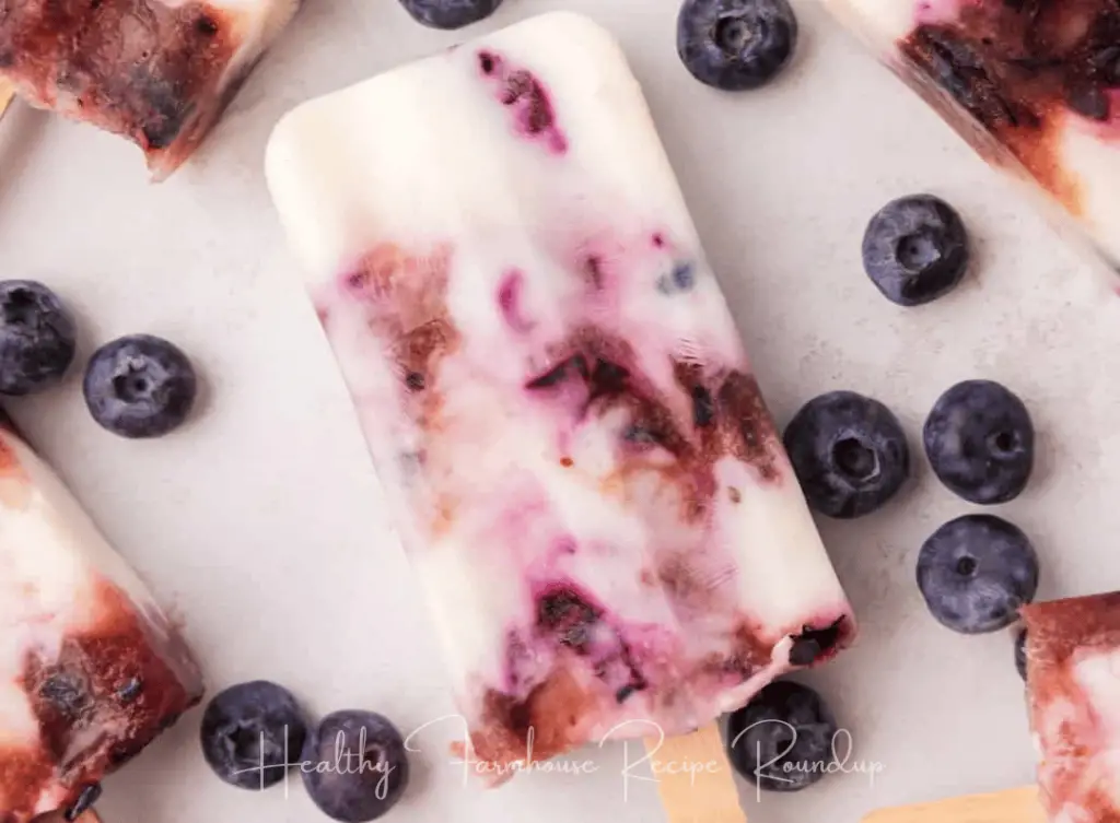 Blueberry yogurt popsicle with blueberries scattered around