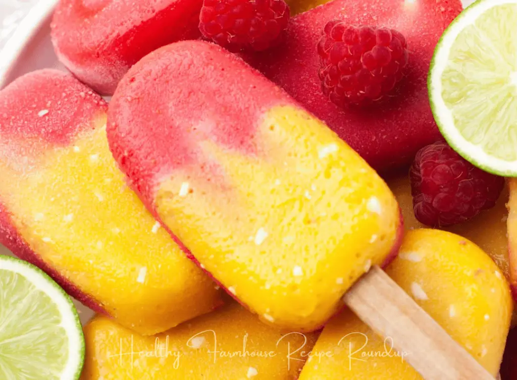 Red and yellow raspberry mango popsicle recipe, featuring lime slices.