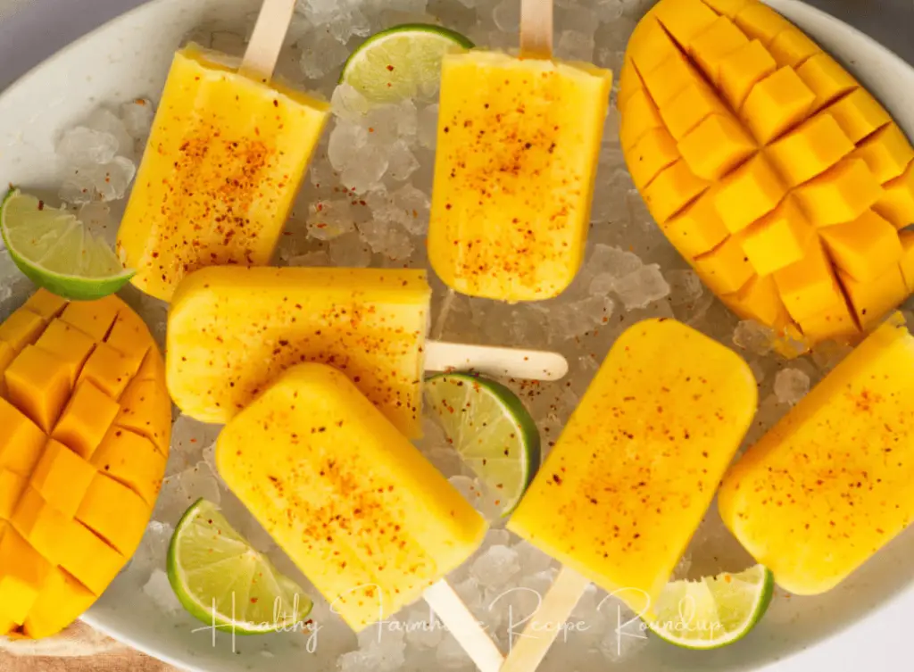 Mango popsicle sprinkled with seasoning in a bowl of ice and limes.