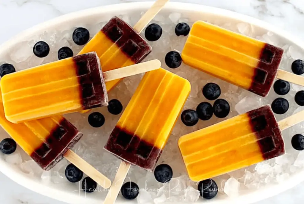 Mango blueberry popsicles in a bowl of ice