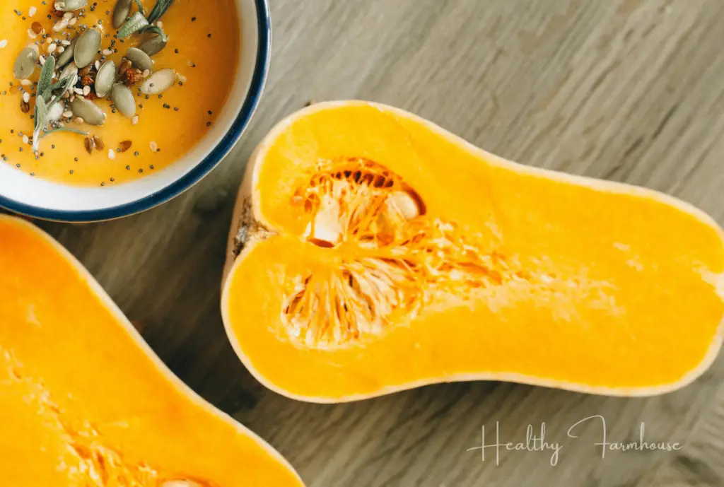 Butternut squash cut in half next to a bowl of soup