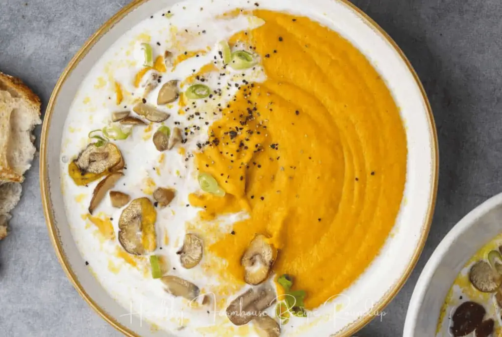Healthy soup recipe - gold and white bowl filled with orange and white soup, topped with mushrooms and seasame seeds