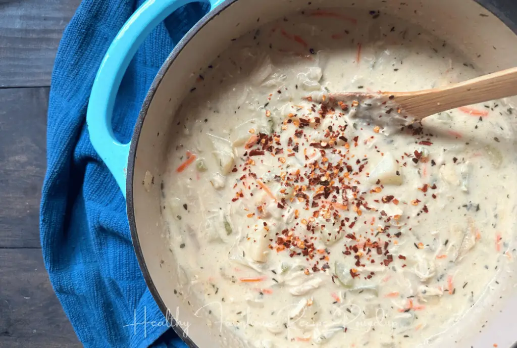 Easy soup recipe - Soup has a white base with veggies and chicken, sprinkle of peppers on top. Served in a blue handled pot.