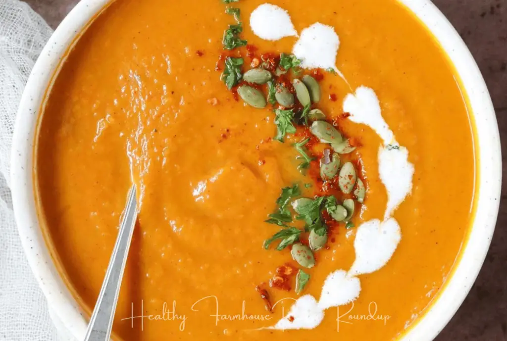 White bowl filled with creamy sweet potato soup with drops of cream and pumpkin seed garnish