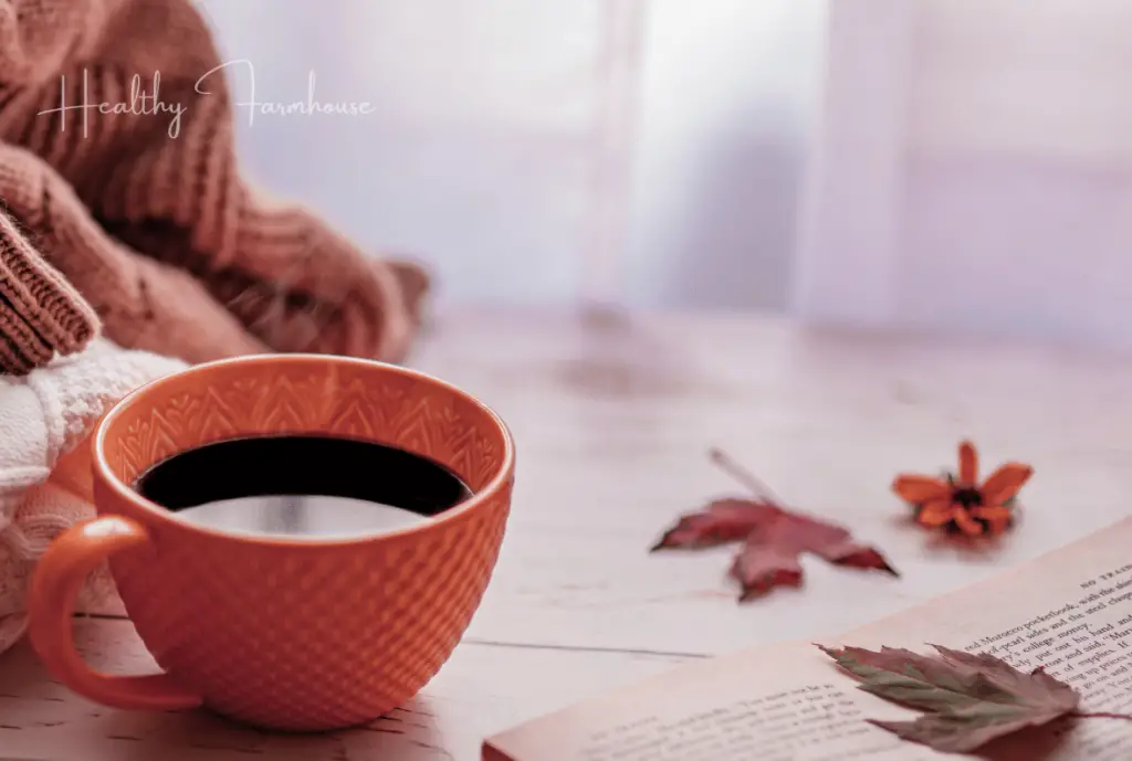 Orange coffee mug with leaves scattered on table