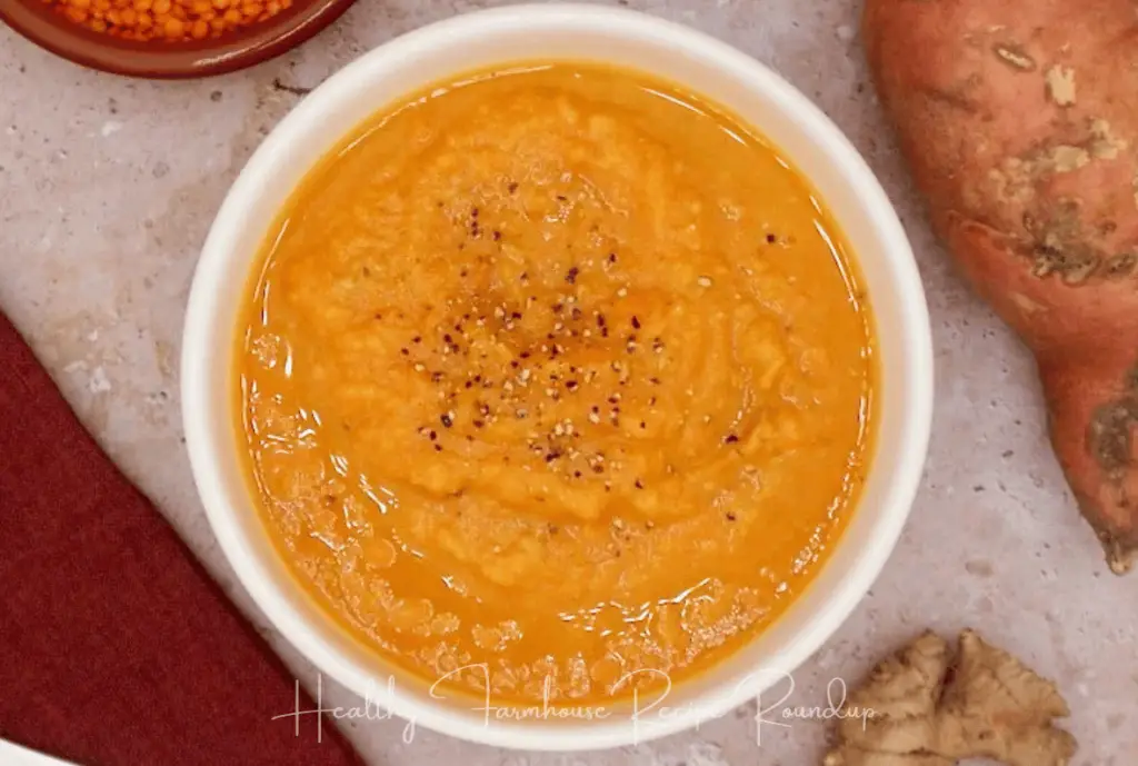 White bowl filled with brightly colored sweet potato and carrot soup.