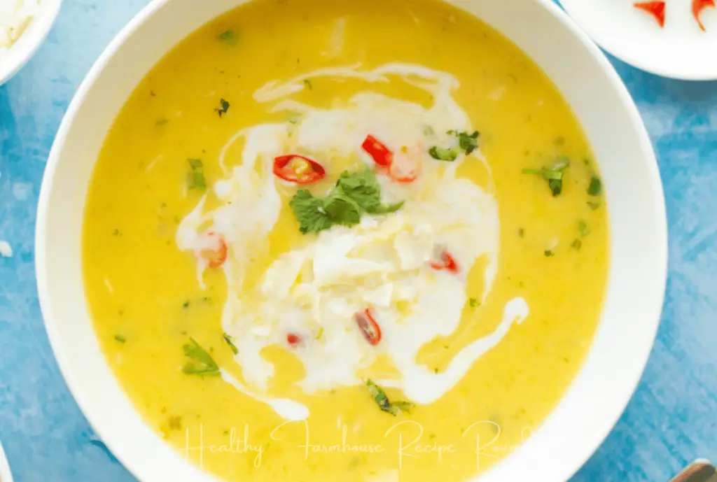 White bowl filled with bright yellow soup and a swirl of cream