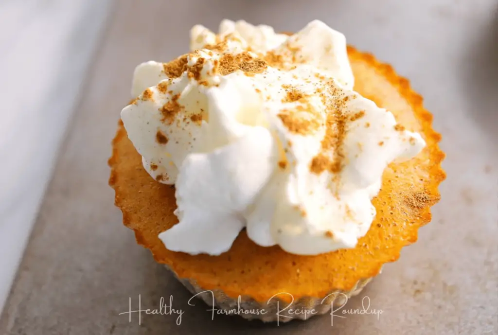 Mini pumpkin pie dessert recipe in a cupcake liner with whipped topping and sprinkle of cinnamon