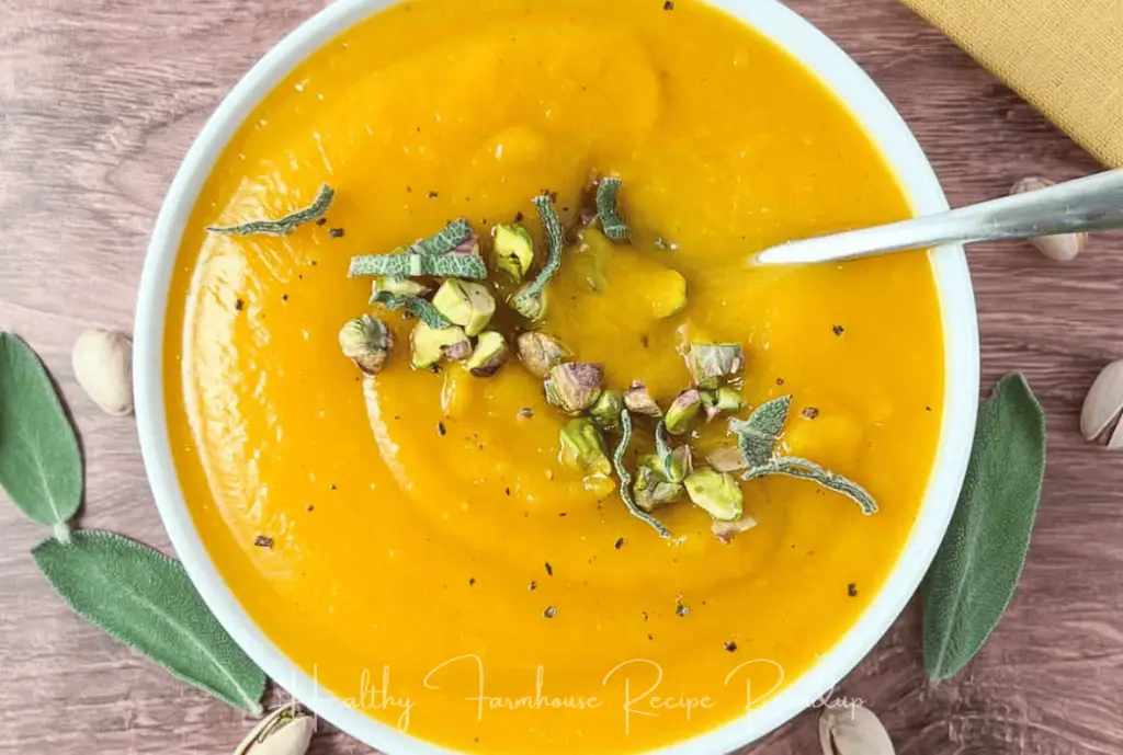 Butternut squash soup recipe in a white bowl with a spoon and sprinkle of pistachios