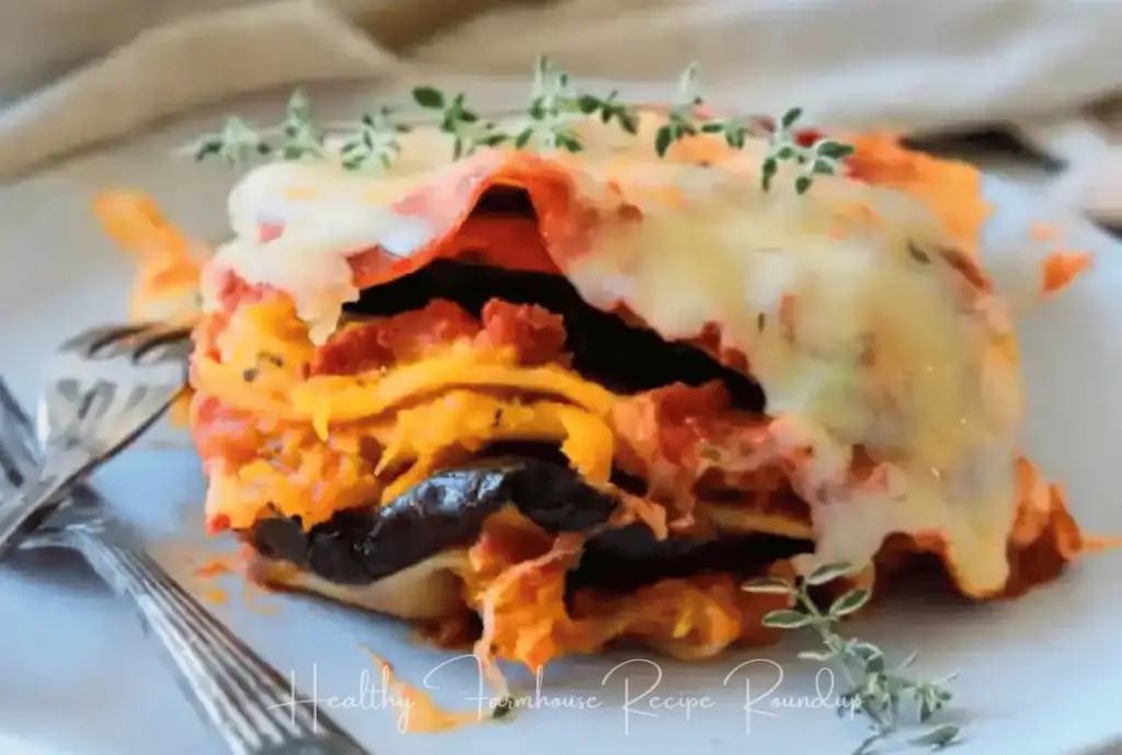 Slice of pumpkin lasagna pasta on a white dish with a fork - garnished with sprigs of thyme