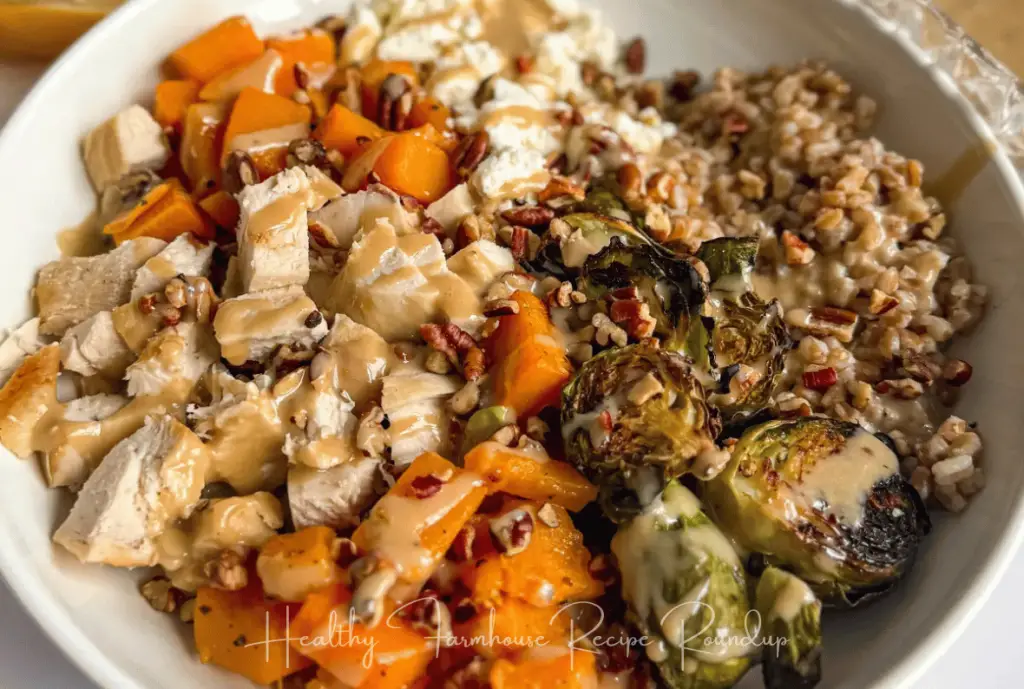 Butternut Squash Dinner bowl filled with chicken cubes, butternut squash cubes, brussels sprouts, and rice, topped with a sauce drizzle.