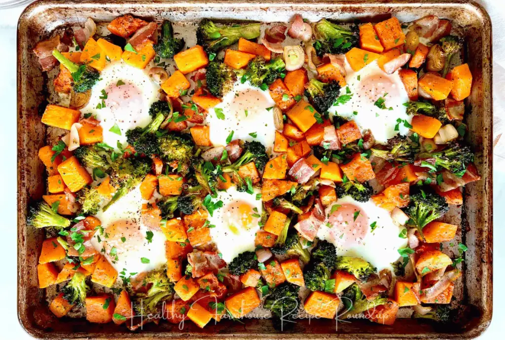 Butternut squash dinner recipe: Sheet pan filled with butternut squash cubes, herbs, and 6 over easy eggs.