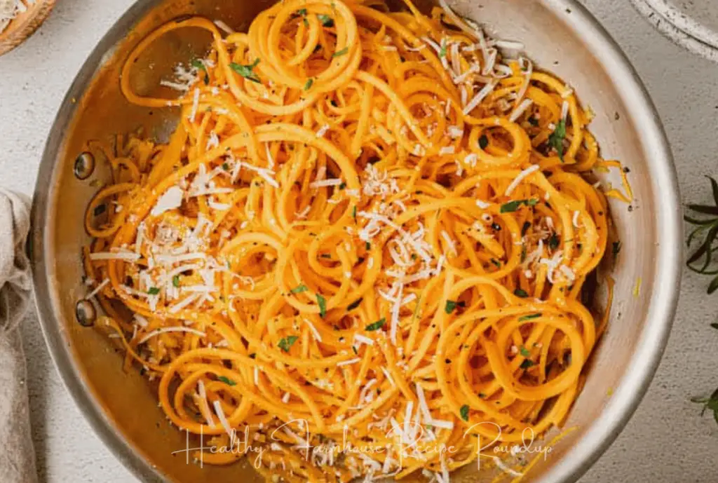 Butternut squash pasta recipe -- orange (butternut squash noodles) served in a metal bowl and topped with cheese.