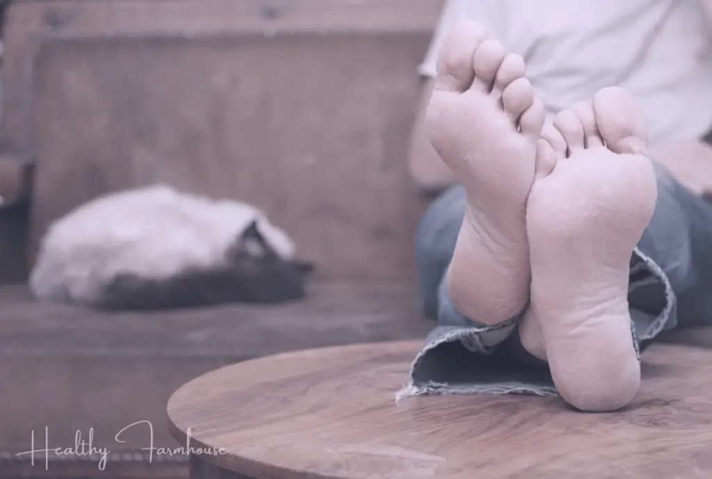 Person with feet kicked up on wooden coffee table with cat sleeping next to them on the couch.