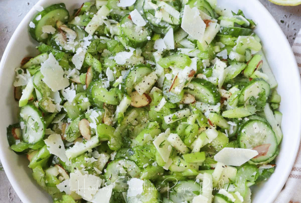 Bright green cucumber salad with cheese and seasonings in a white bowl