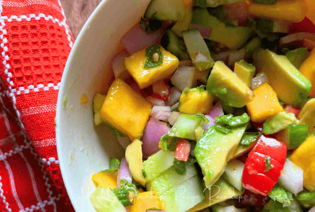Avocado, mango salad with cucumbers and tomatoes in a white bowl