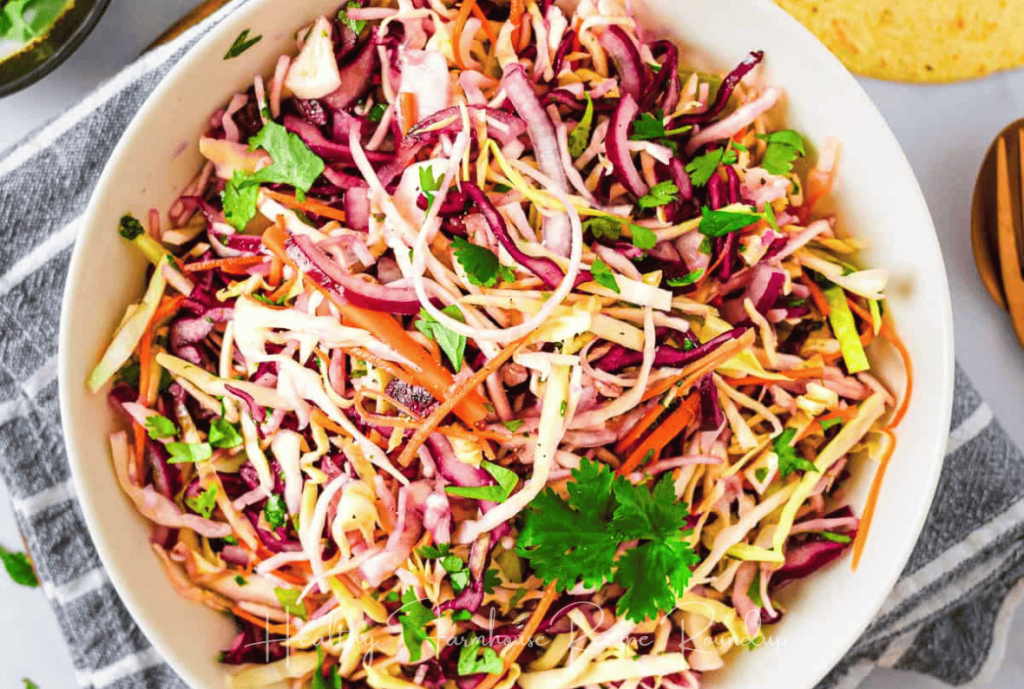 Colorful mexican coleslaw recipe with cilantro leaves in a white bowl