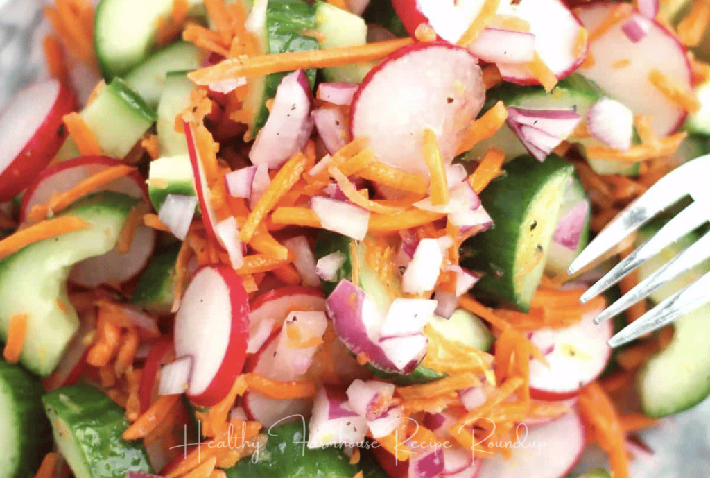 Very vibrant and colorful cucumber salad with green cucumbers, red radishes, and orange carrot shreds.