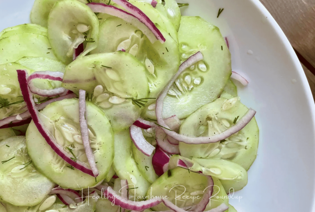 Vinegar based cucumber salad recipe with red onions on a white plate