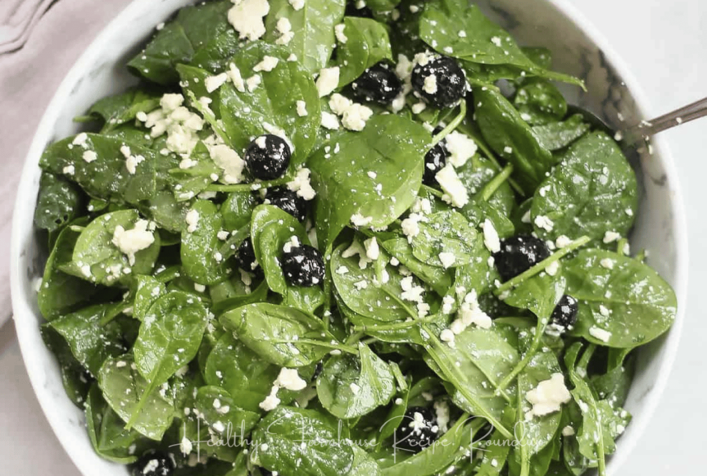 Green salad in white bowl with sprinkles of feta cheese