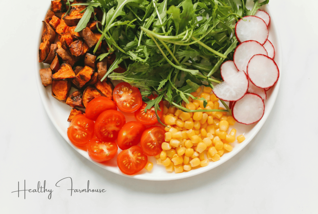 Summer dinner plate with meat, greens, corn, radishes, tomatoes